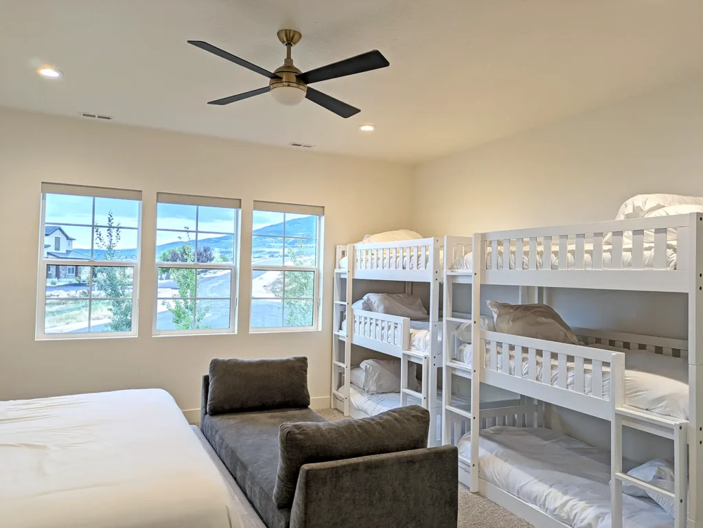 Bedroom with ceiling lights, fan, beds, and windows